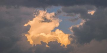 A captivating cloudscape featuring golden clouds illuminated by the setting sun, creating a serene and ethereal atmosphe