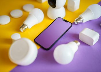 Colorful flat lay of smart home devices and smartphone on vibrant background, ideal for technology concepts.