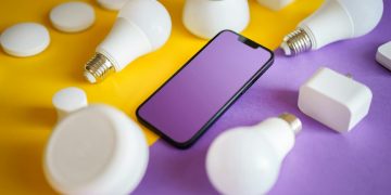 Colorful flat lay of smart home devices and smartphone on vibrant background, ideal for technology concepts.