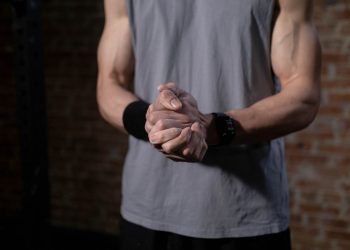 Close-up of a person's muscular arms with clasped hands, conveying strength and focus.