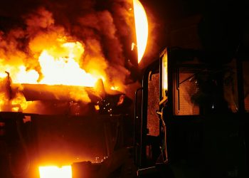 A dramatic scene of molten steel pouring in an industrial setting during nighttime.
