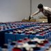 A worker checking many industrial batteries inside a facility. Indoor, industrial setting.
