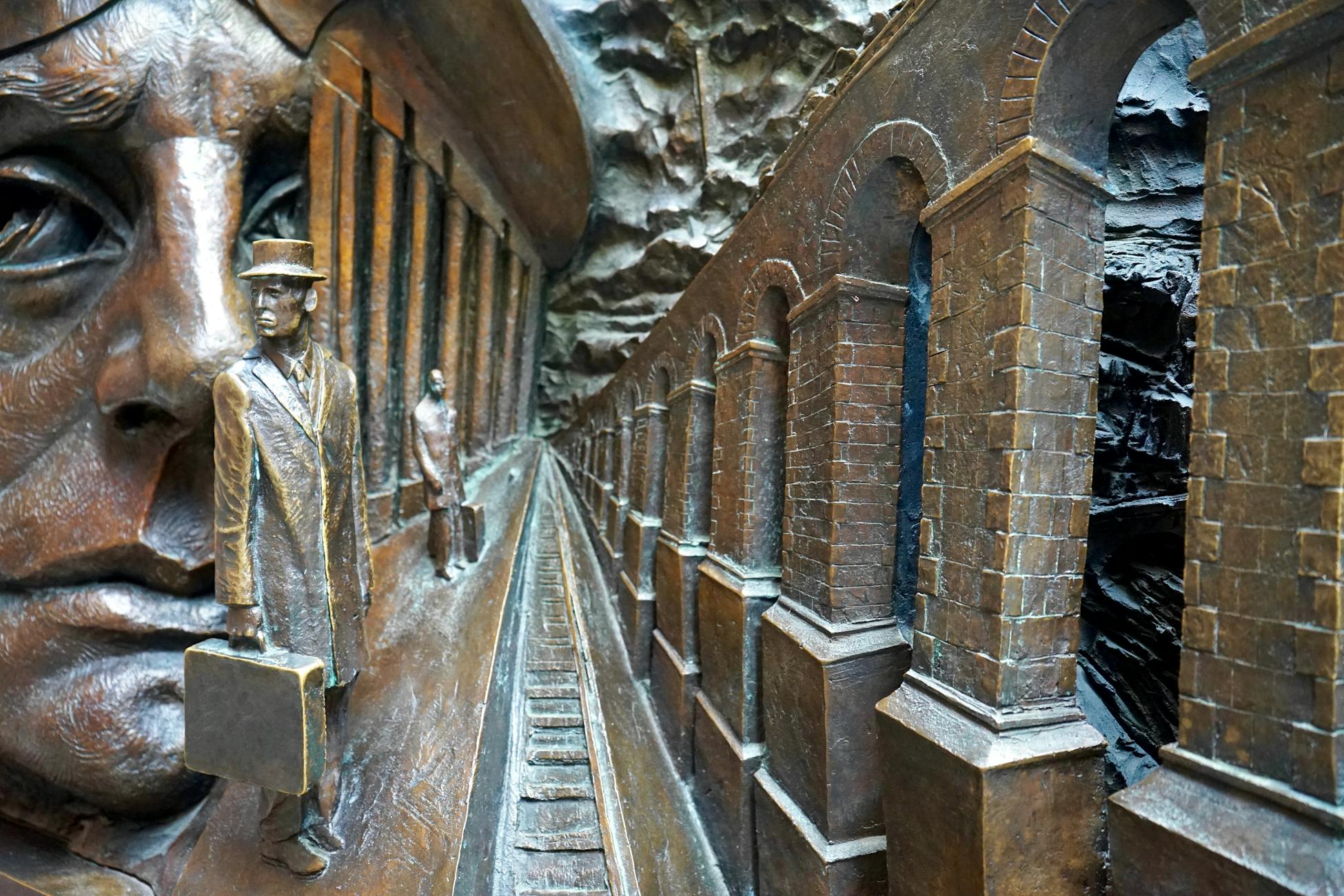 Detailed close-up of a bronze sculpture depicting a historical scene with figures and architectural elements.