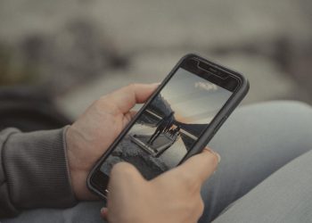 Close-up of hands holding a smartphone showing a mountain scene, captured outdoors in Banff.