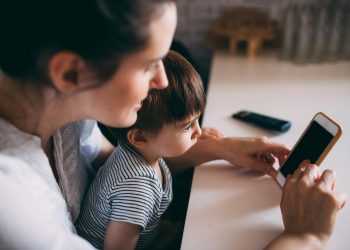 A mother and child bonding while using a smartphone at home.