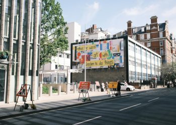 City street scene with a colorful billboard and road closure signs.
