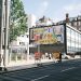 City street scene with a colorful billboard and road closure signs.