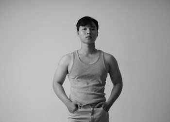 Stylish black and white portrait of an Asian man wearing a tank top in a studio setting.