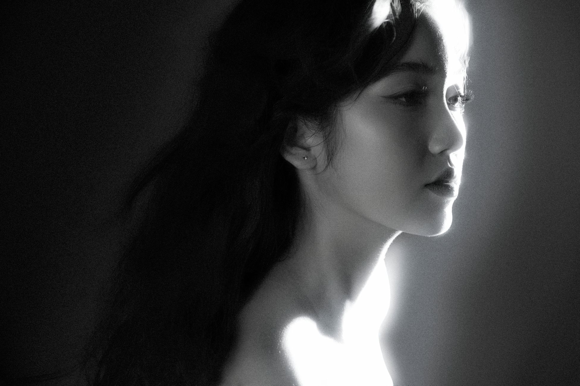 Artistic black and white profile portrait of a woman in soft lighting.