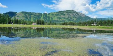 A serene mountain lake reflecting blue skies and lush greenery, perfect for nature lovers.