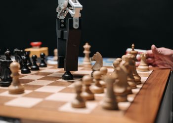 Close-up of a robotic arm playing chess against a human, showcasing AI technology in a classic board game setting.