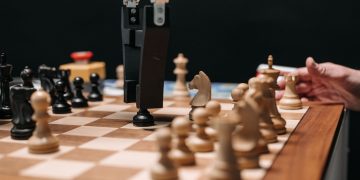 Close-up of a robotic arm playing chess against a human, showcasing AI technology in a classic board game setting.