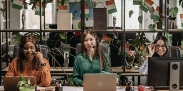 A multicultural group of women working in a modern office setting, showcasing teamwork.