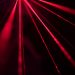 Dynamic red laser beams create a striking abstract pattern in a dark studio setting.