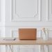 A serene workspace featuring a simple desk with a laptop, notebook, and a vase of flowers.