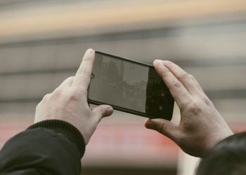 Close-up of hands using a smartphone to capture a photo outdoors.