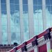 Glass facade reflecting clouds against a decorative urban building.