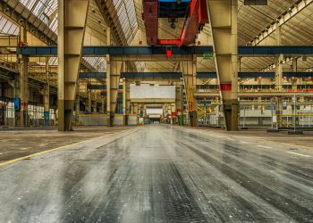Wide view of an empty industrial warehouse with visible cranes and metal structures.