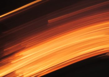 Captivating abstract motion blur with vibrant orange and dark tones, evoking the fluidity and energy of fire.