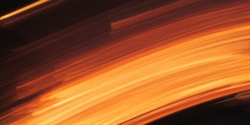 Captivating abstract motion blur with vibrant orange and dark tones, evoking the fluidity and energy of fire.
