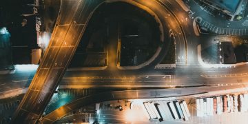 Top-down view of a city intersection with traffic and infrastructure at night.