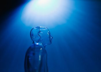 Transparent robotic figure illuminated by blue light, symbolizing AI and futuristic technology.