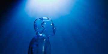 Transparent robotic figure illuminated by blue light, symbolizing AI and futuristic technology.