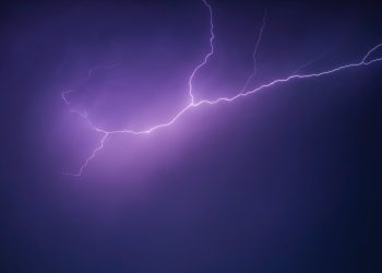 A striking image of a purple lightning bolt illuminating the night sky, creating a dramatic and moody scene.