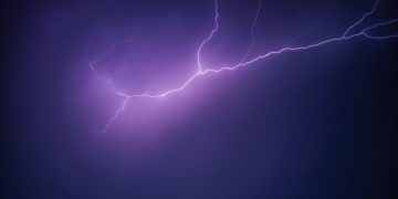A striking image of a purple lightning bolt illuminating the night sky, creating a dramatic and moody scene.