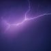 A striking image of a purple lightning bolt illuminating the night sky, creating a dramatic and moody scene.