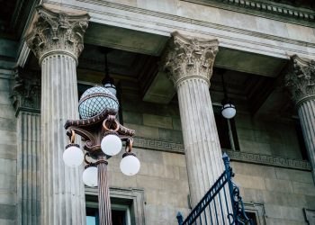 An elegant view of classic architectural columns with an antique street lamp, ideal for urban landscapes.