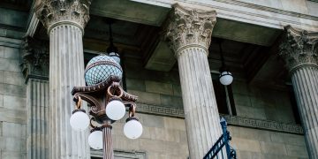 An elegant view of classic architectural columns with an antique street lamp, ideal for urban landscapes.