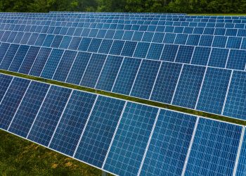 High angle pole mounted solar energy trackers installed on green field in solar power station