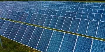 High angle pole mounted solar energy trackers installed on green field in solar power station