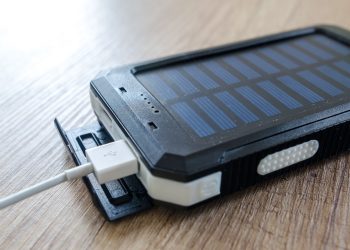 A close-up of a solar charger with a USB connection on a wooden surface, showcasing modern technology.