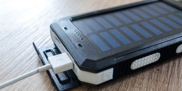 A close-up of a solar charger with a USB connection on a wooden surface, showcasing modern technology.
