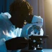 A scientist in protective clothing uses a microscope for research in a laboratory setting.