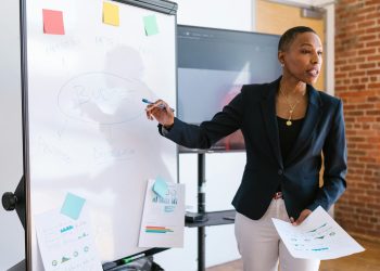 Professional businesswoman explaining budget strategy on a whiteboard during a meeting.