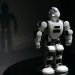 White robot toy casting a shadow in a dark studio setting, highlighting artificial intelligence.