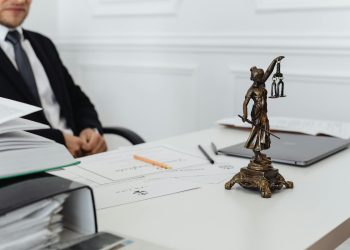 A legal professional's workspace featuring Lady Justice statue, documents, and a laptop.