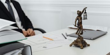 A legal professional's workspace featuring Lady Justice statue, documents, and a laptop.