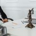 A legal professional's workspace featuring Lady Justice statue, documents, and a laptop.
