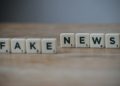 Scrabble tiles spelling 'Fake News' on a wooden surface highlighting misinformation.