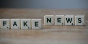 Scrabble tiles spelling 'Fake News' on a wooden surface highlighting misinformation.