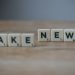 Scrabble tiles spelling 'Fake News' on a wooden surface highlighting misinformation.