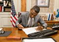 Professional man signs contract at desk in classic office environment.