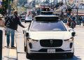 A self-driving car navigates through a bustling city street in San Francisco, capturing urban mobility in action.