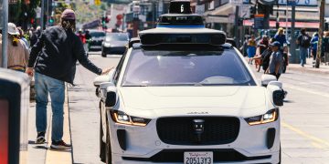 A self-driving car navigates through a bustling city street in San Francisco, capturing urban mobility in action.