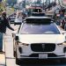 A self-driving car navigates through a bustling city street in San Francisco, capturing urban mobility in action.