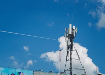 Cell tower against a bright blue sky with clouds